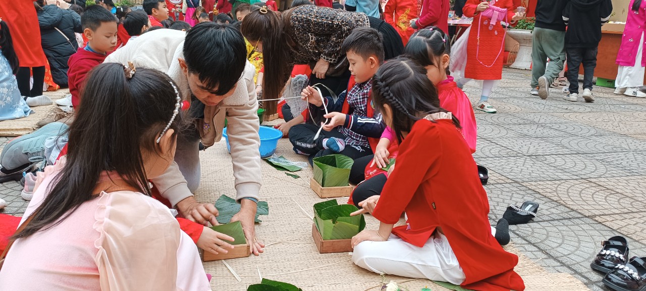 Cha mẹ học sinh đang hướng dẫn các con em mình cách gói bánh chưng