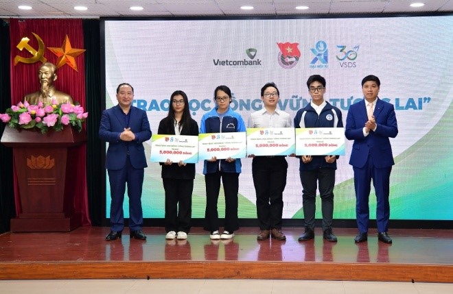 Đ/c Hồng Quang – Thành viên HĐQT kiêm Giám đốc Khối Nhân sự, Chủ tịch Công đoàn Vietcombank (ngoài cùng bên phải) và đ/c Vy Tư Liệu – Vụ trưởng Vụ Đoàn thể nhân dân, Ban Dân vận Trung ương (ngoài cùng bên trái) trao học bổng cho các bạn học sinh, sinh viên có hoàn cảnh khó khăn