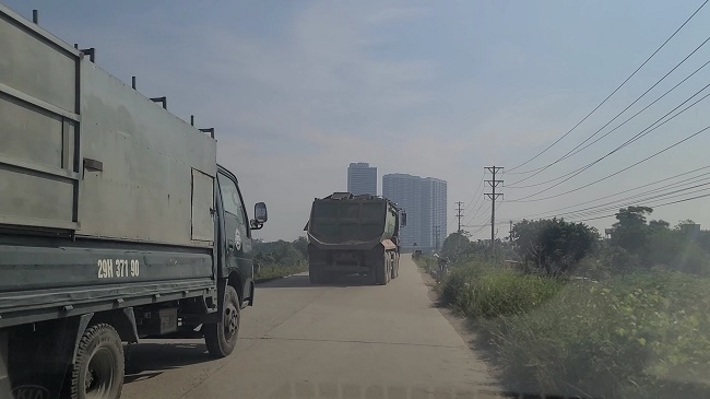 Những chiếc xe chở cát có dấu hiệu quá tải chạy trên bờ đê.