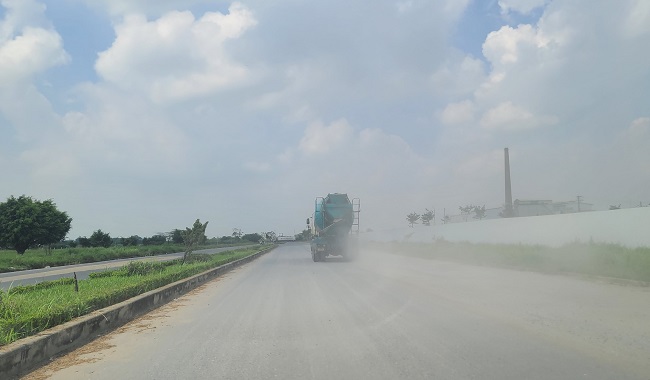 Những chiếc xe bê tông tươi chạy trên đường khiến bụi mù mịt.