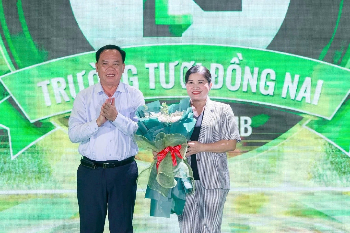 Ông Võ Tấn Đức, Chủ tịch UBND tỉnh Đồng Nai trân trọng trao bó hoa tươi thắm đến bà Trần Tuệ Hiền, nguyên Chủ tịch UBND tỉnh Bình Phước.