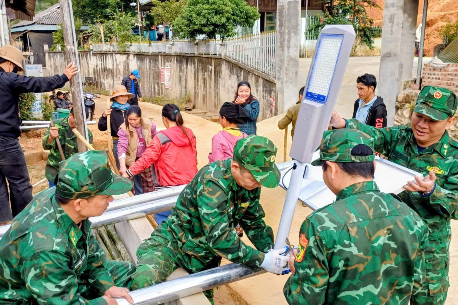 Cán bộ, chiến sĩ Đồn Biên phòng Na Mèo giúp dân dựng cột đèn năng lượng mặt trời. 