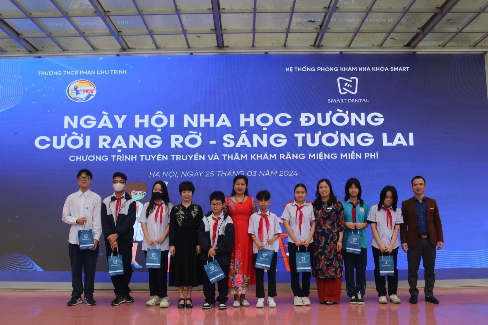 (Bà Phan Châu Giang, Giám đốc truyền thông Hệ thống Nha khoa Smart cùng Ban Giám hiệu nhà trường trao quà đến các em học sinh.)